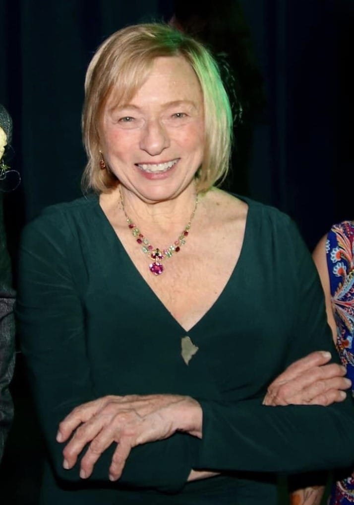 Governor Janet Mills posed with arms crossed and a big smile, wearing the Maine State Tourmaline Necklace.