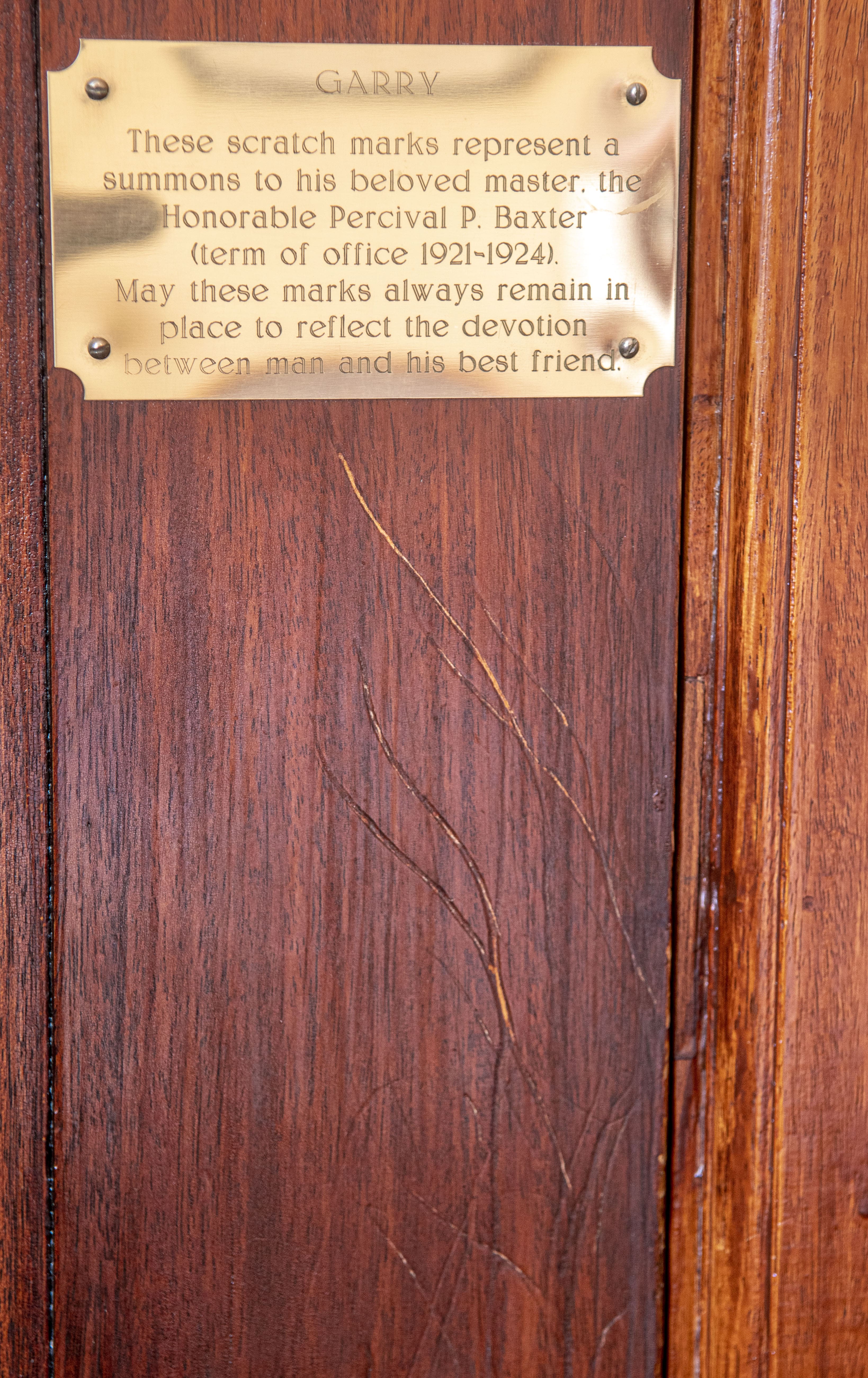 Wooden door with scratch marks and a metal placard.