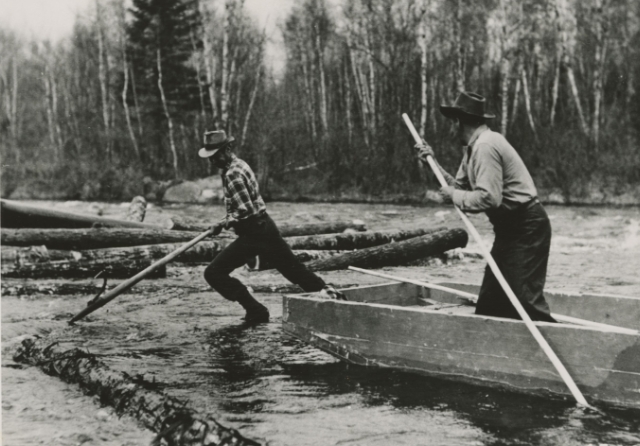 Black and white photo of loggers on the water