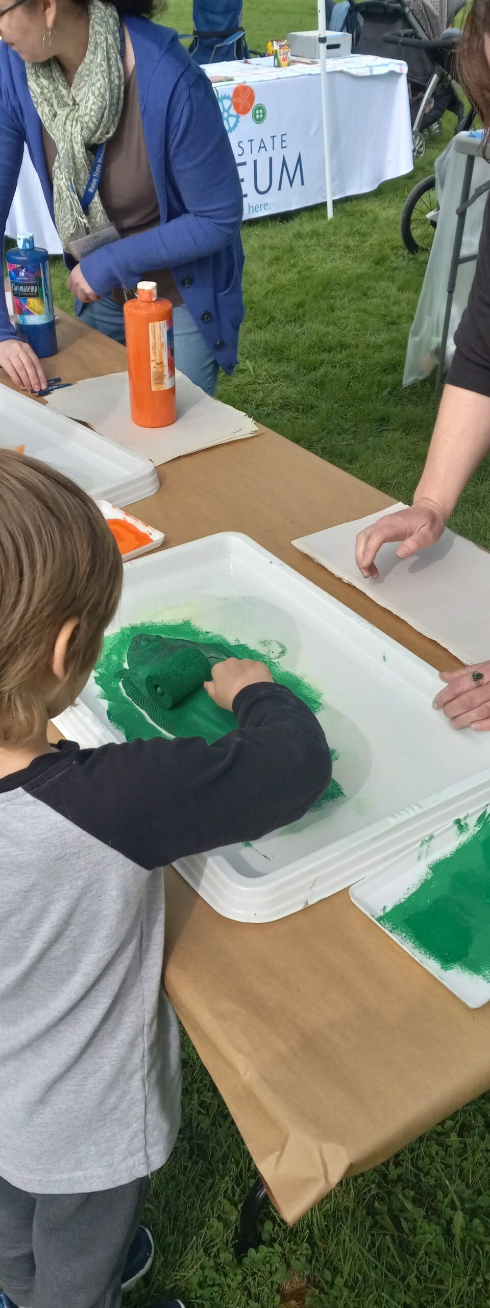 Child using paint roller to create a craft at an event