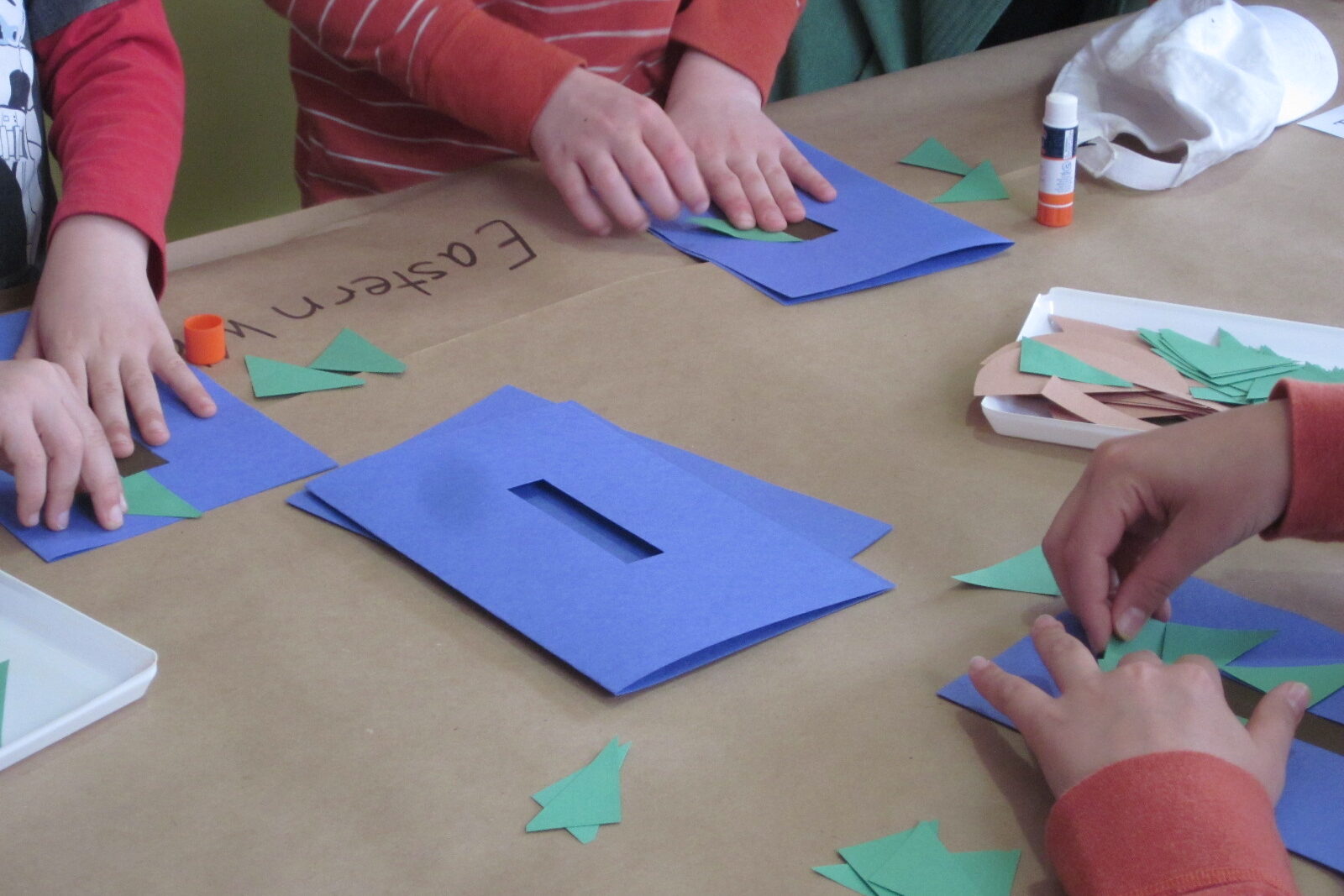children's hands assembling construction paper project