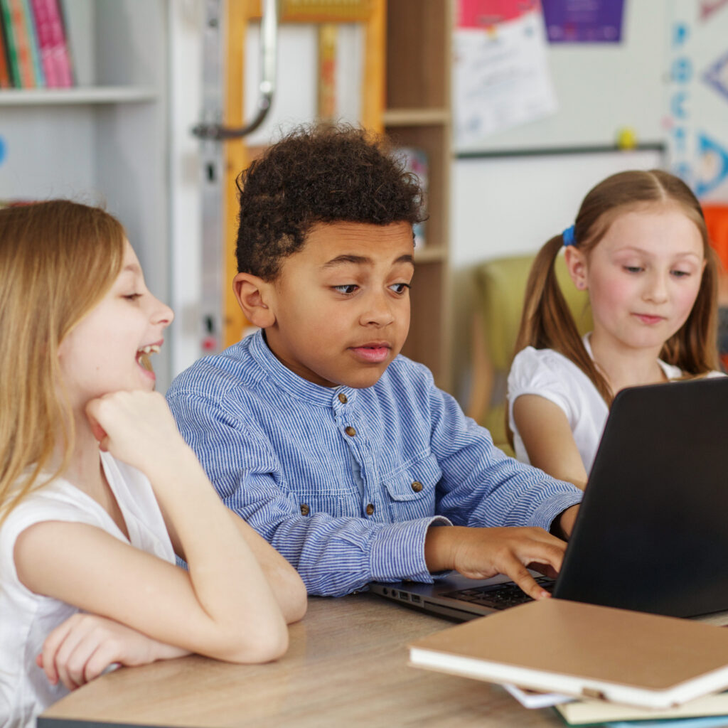 Group of children sitting in a row in a school classroom and studying and talking.